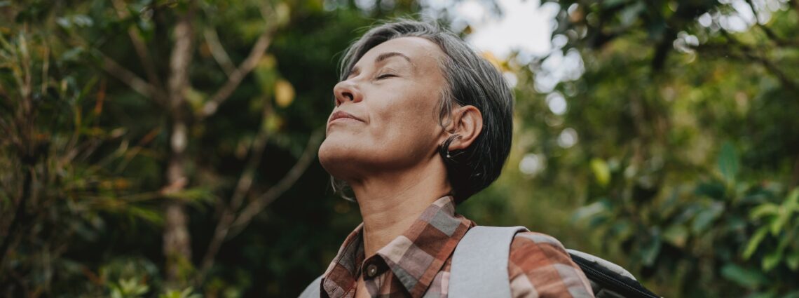 A woman over 50 with eyes closed in soft natural light representing surrender, release, and letting go of the outcome.
