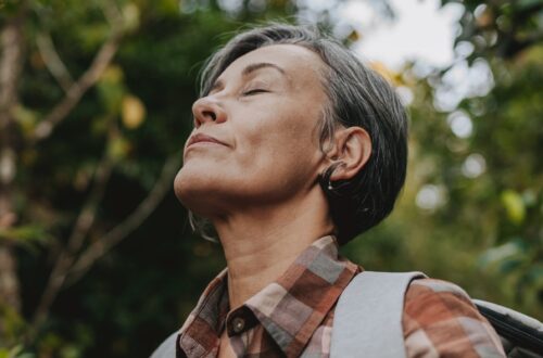 A woman over 50 with eyes closed in soft natural light representing surrender, release, and letting go of the outcome.