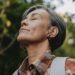 A woman over 50 with eyes closed in soft natural light representing surrender, release, and letting go of the outcome.
