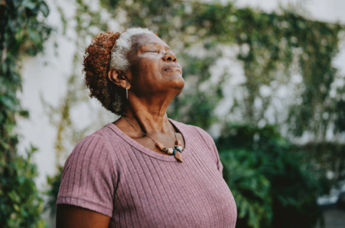 Woman over 50 standing outdoors with eyes closed in peaceful meditation